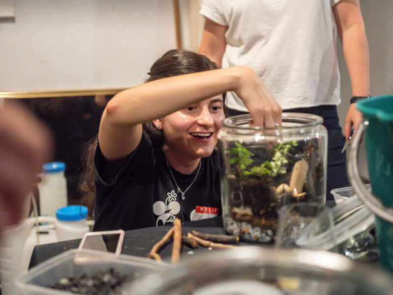 A person adds finishing touches to their DIY terrarium.